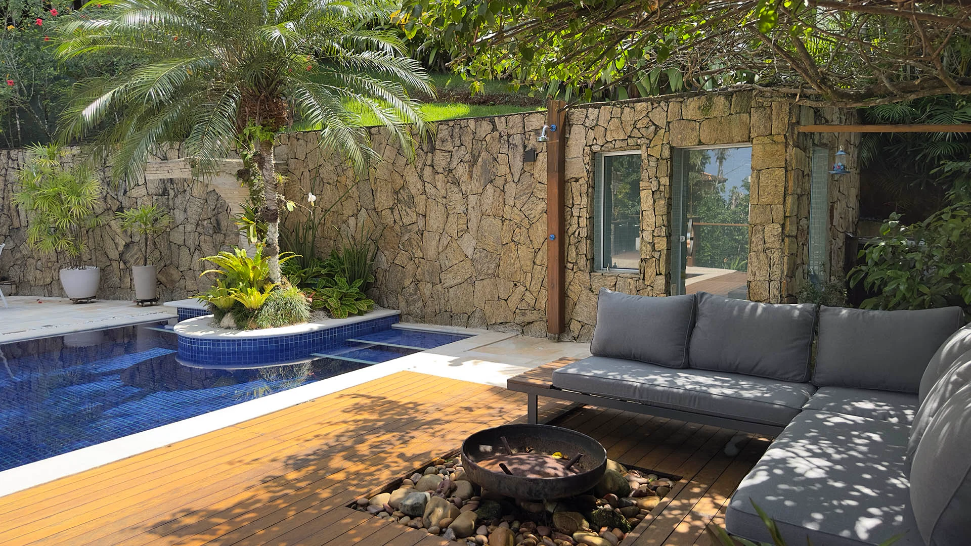 Lounge com lareira de chão e pergolado com bougainville na área da piscina
