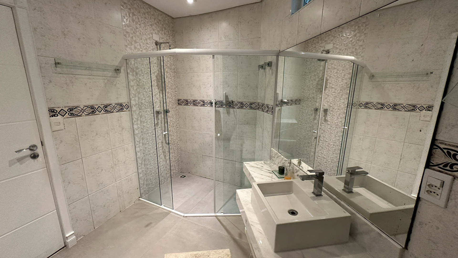 Banheiro de suíte com boxe branco e porcelanato em estilo marmore