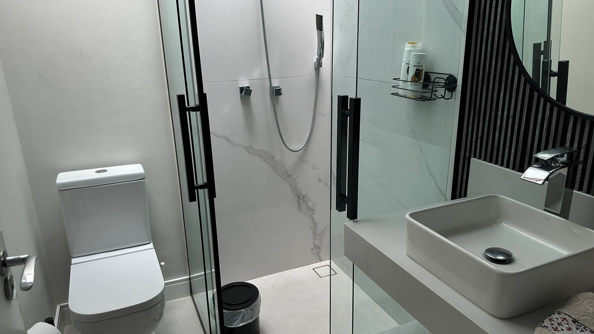 Banheiro compacto com boxe preto e porcelanato estilo mármore